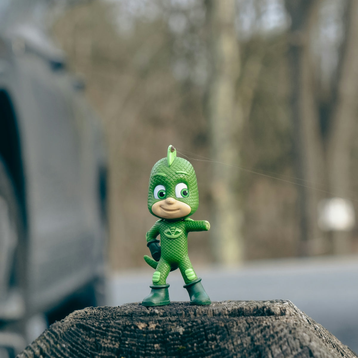 a toy figurine of a green bird on top of a tree stump