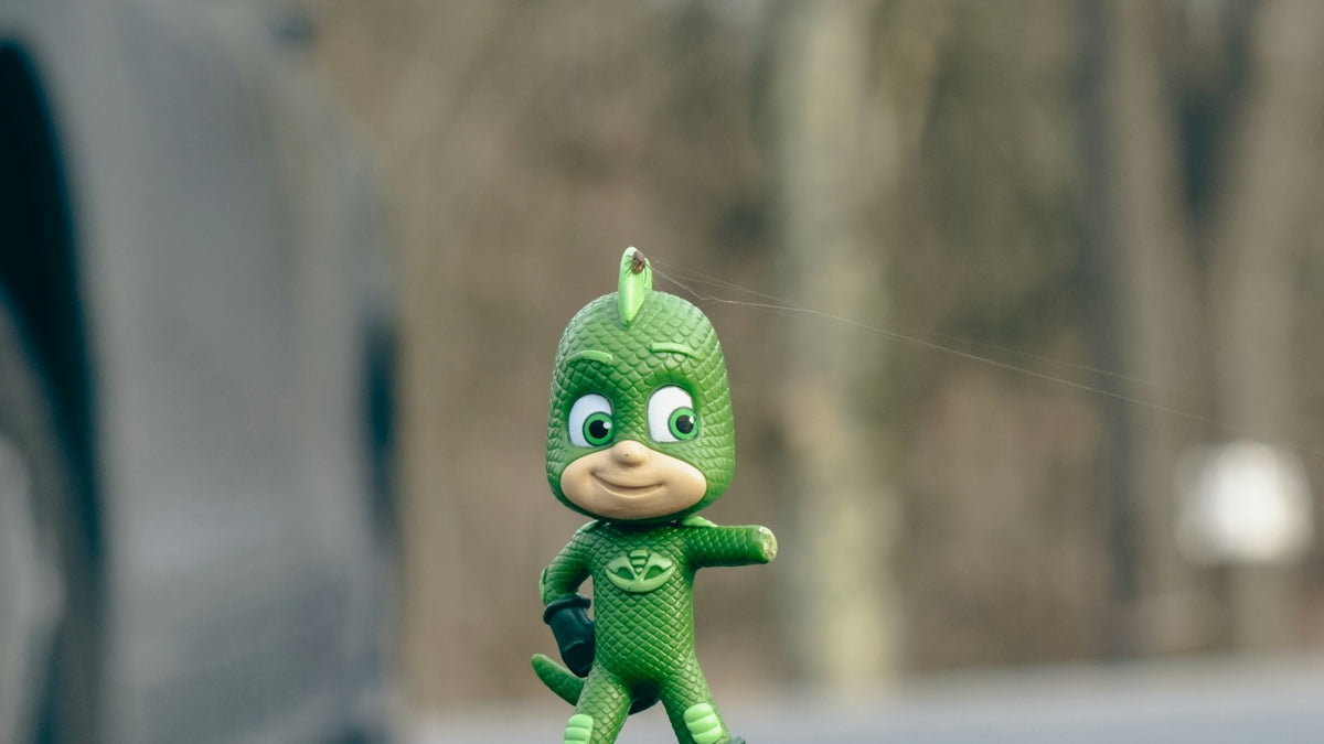 a toy figurine of a green bird on top of a tree stump