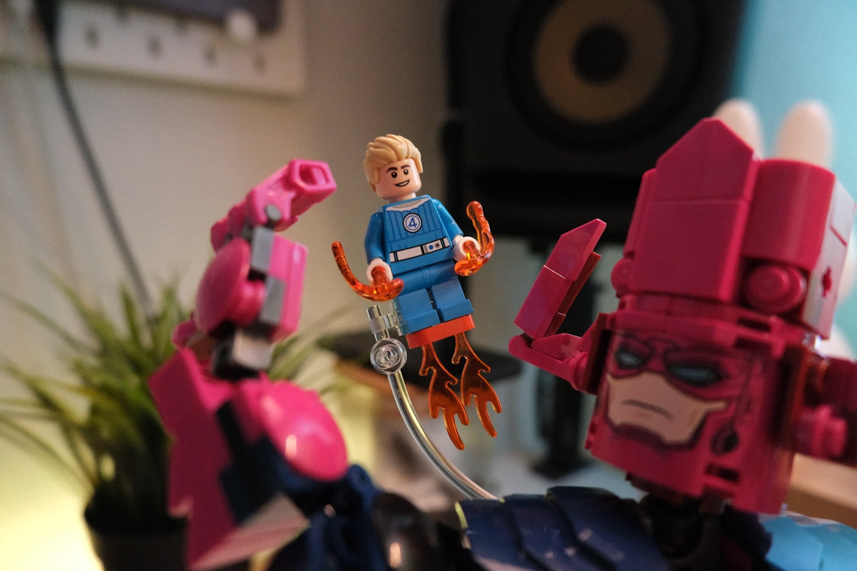 Lego human torch minifigure flying between two large robot figures.
