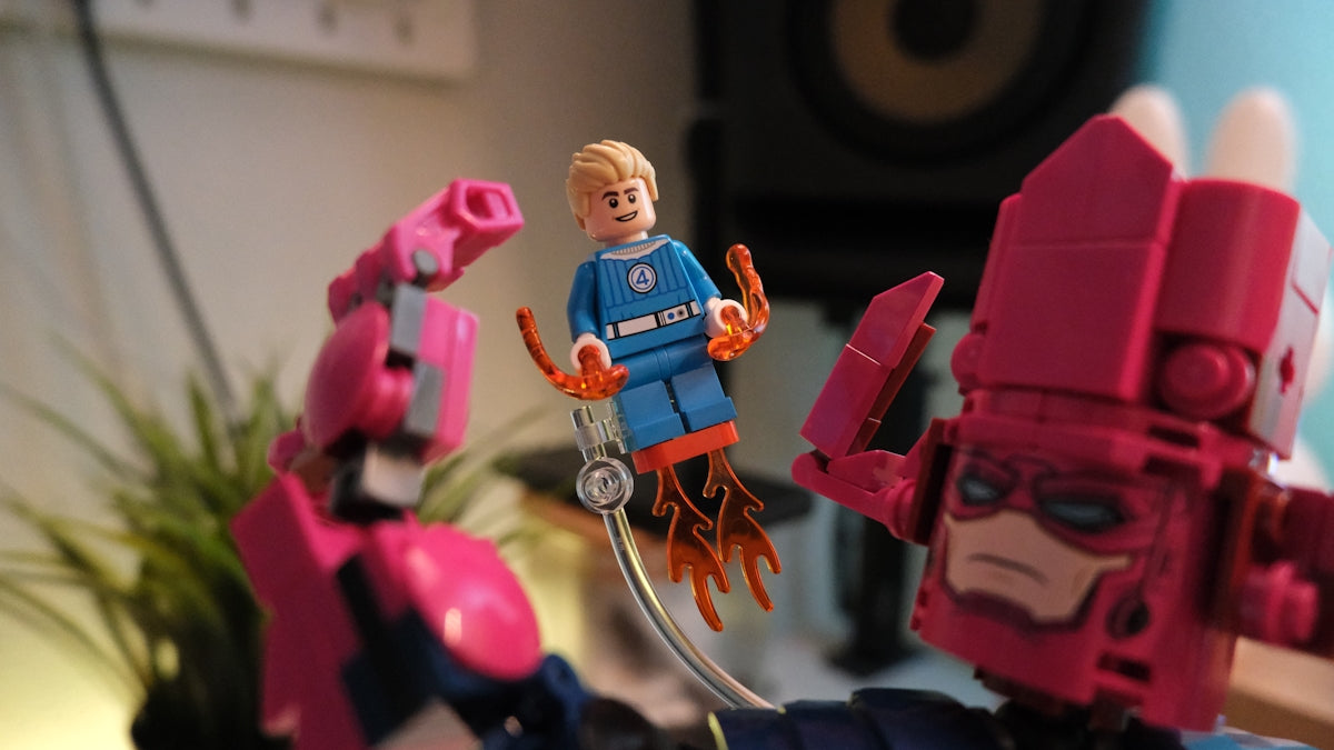 Lego human torch minifigure flying between two large robot figures.