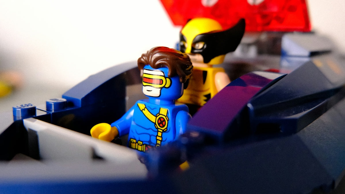 Cyclops and wolverine lego minifigures in a blue vehicle.