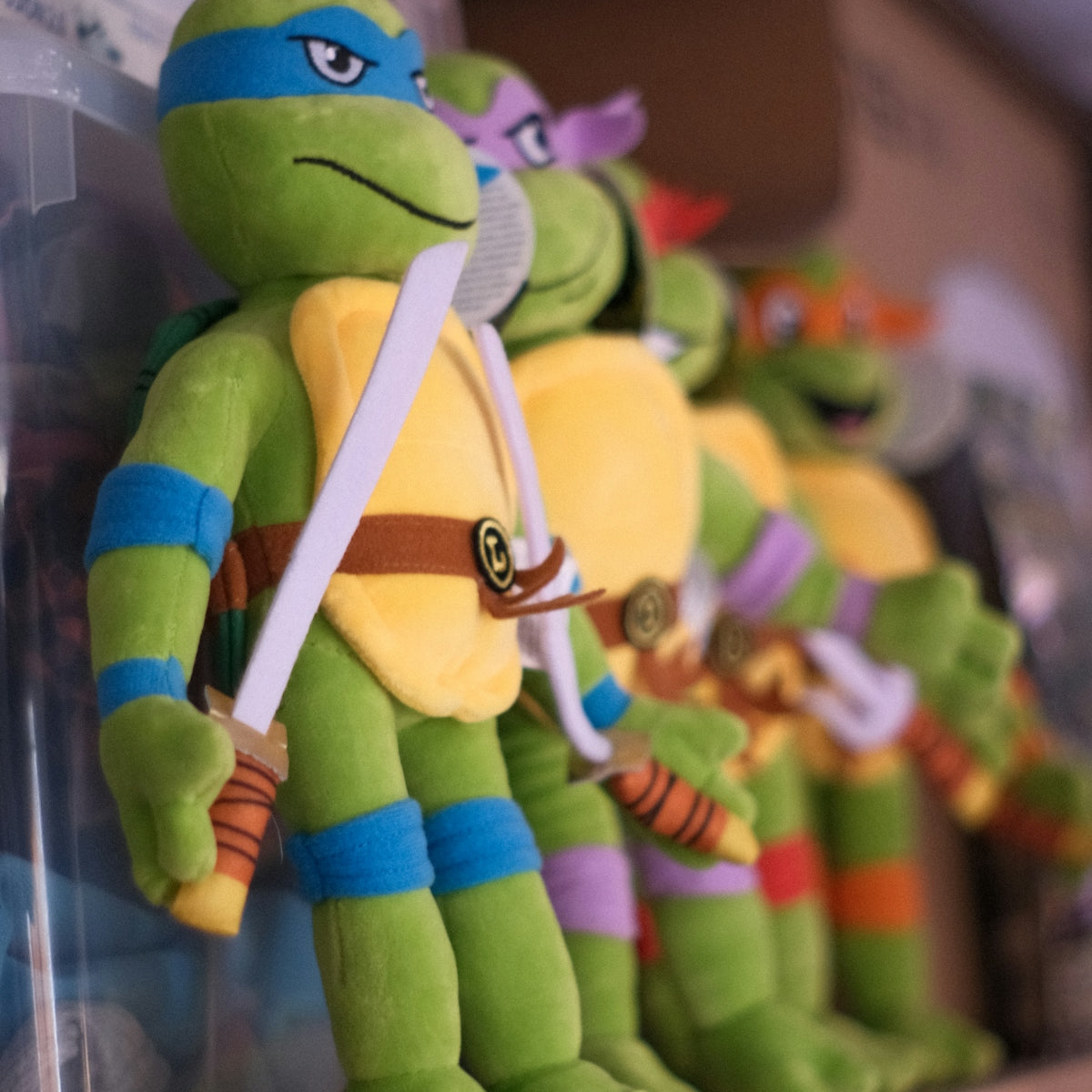 Four teenage mutant ninja turtles plush toys on a shelf.