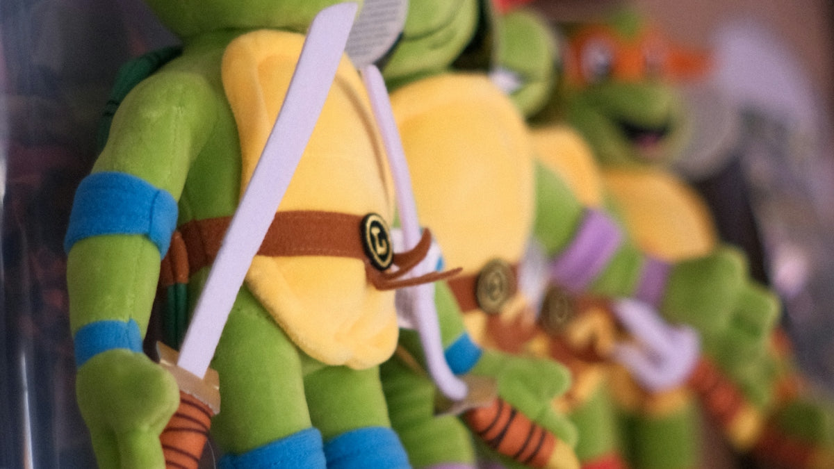 Four teenage mutant ninja turtles plush toys on a shelf.