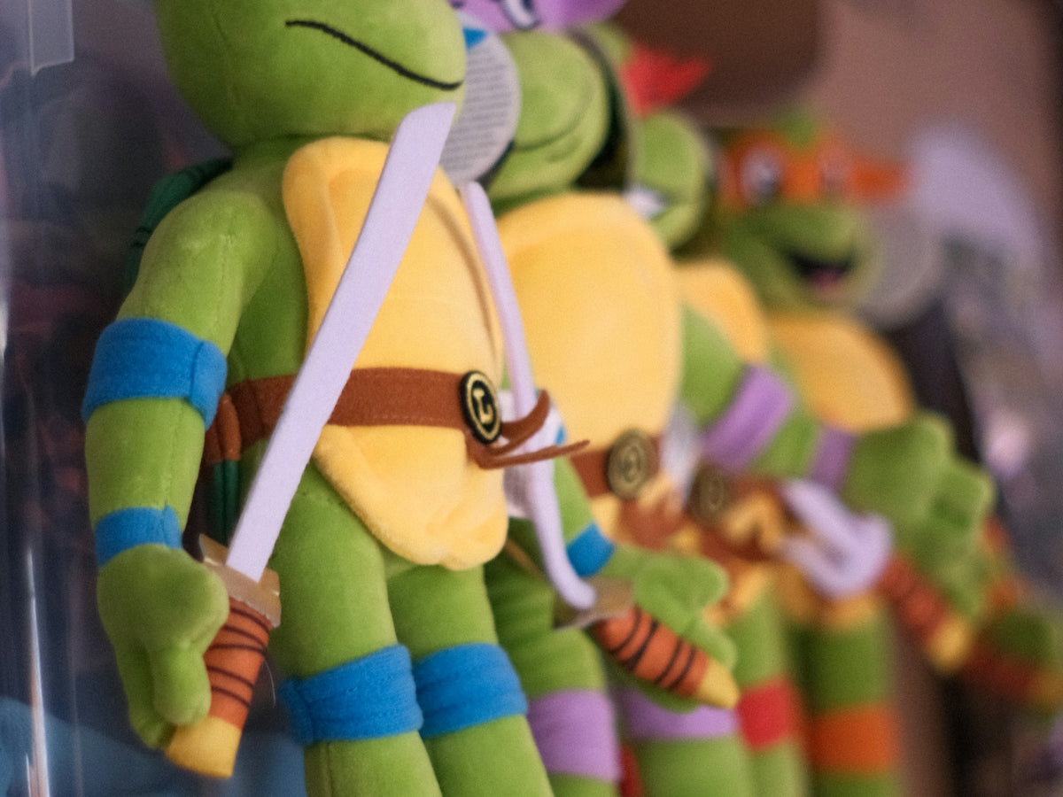 Four teenage mutant ninja turtles plush toys on a shelf.